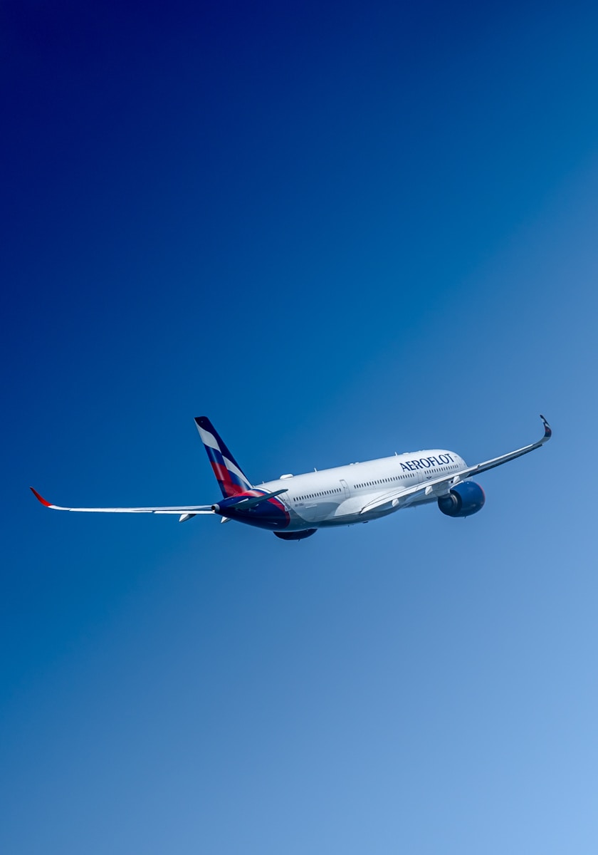 Photo by Soekarno Omar a large commercial airplane flying through a blue sky